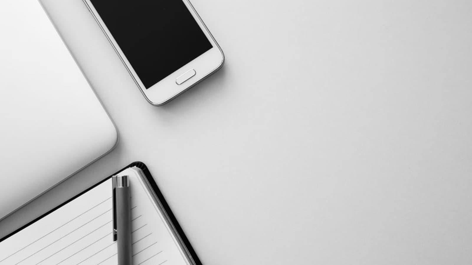 Smartphone on a desk next to a notebook